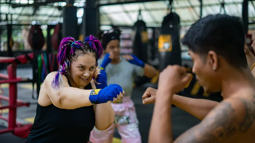 A woman training in Muay Thai with her trainer in a weight loss resort in Thailand